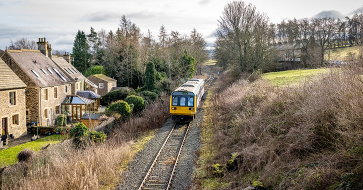 View of Weardale Railway - train on tracks passing houses in countryside